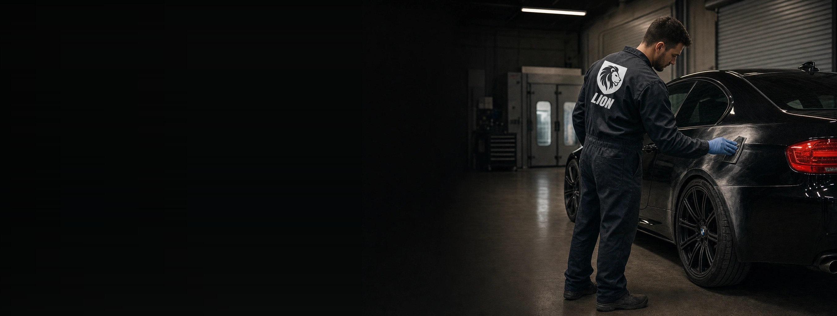 A Lion Collision Center technician block-sanding the rear quarter of a black BMW in the shop
